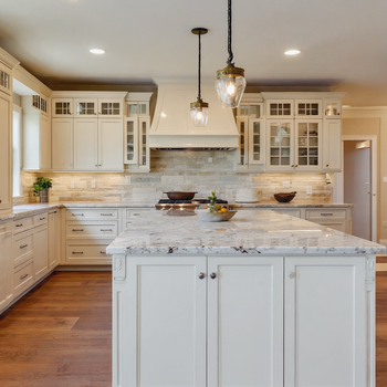 Luxury white farmhouse kitchen with marble island, custom cabinets, pendant lighting, and hardwood floors