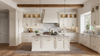 Luxury white farmhouse kitchen with marble backsplash, large island, brass fixtures, pendant lighting, and exposed wood ceiling beam