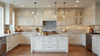 Modern white shaker kitchen with marble island, pendant lighting, stainless steel appliances and gray stone backsplash